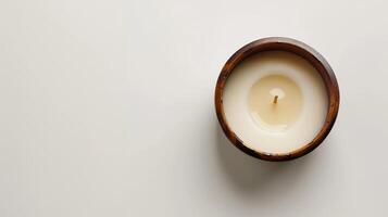 Top view of a round white aromatic candle with a wooden wick in a wooden bowl photo