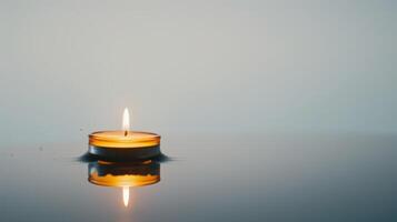 Serene and peaceful atmosphere is created by a small candle floating on water with a reflection photo
