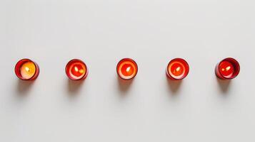Five red aromatic candles burning with yellow flame on white background creating cozy atmosphere photo