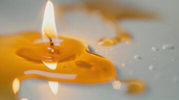 Candle is burning with melted wax around and water droplets on the surface photo