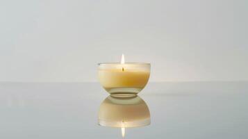Round candle burns brightly on a reflective surface against a white backdrop photo