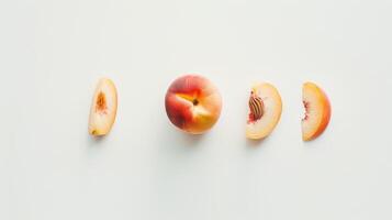 Whole peach and peach slices arranged on a white surface. photo