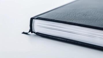 Black leather-bound thick book resting on white surface, displaying its blank pages photo