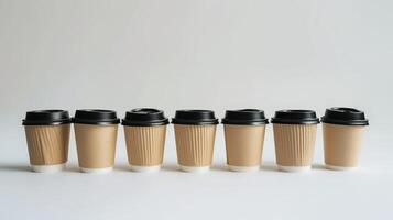 Seven disposable coffee cups with black lids standing in line on a white background photo
