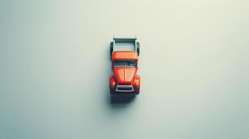 Small red toy pickup truck sits on a simple backdrop, creating a soft shadow photo
