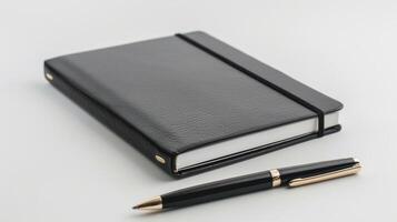 Stylish pen next to a black leather notebook with elastic closure on a white desk photo