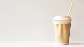 Paper coffee cup with a paper straw sits on a white table against a white backdrop photo