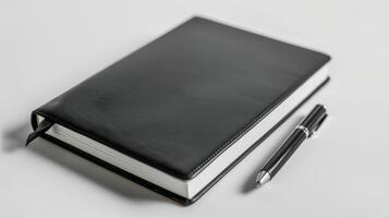 Black leather notebook and pen rest on a tidy white desk photo