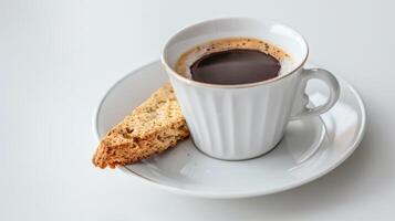 White coffee cup on a saucer with a cantuccini cookie on the side photo