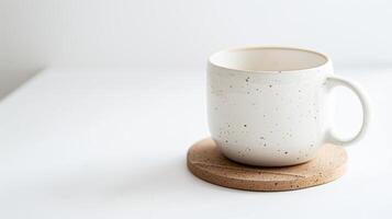 White speckled ceramic coffee mug sits on a cork coaster on a smooth white surface photo