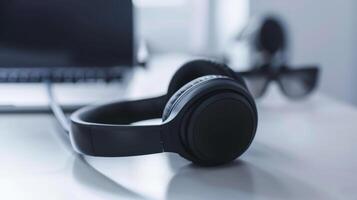 Modern freelancer workspace with black headphones, a laptop, a microphone, and sunglasses on desk photo