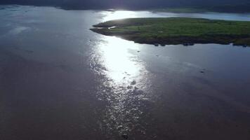 Sunset view over mountains by the lake and vast green fields under cloudy sky in rainy season. video