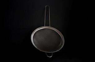A metal mesh strainer on a black background photo