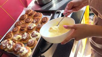 spread cinnabon special spatula spreading a white butter cream on fresh hot cinnamon buns with spices in slow motion close up 4K . video