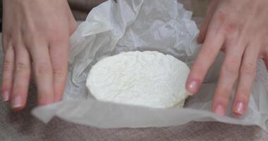 hands unwrap new fresh Camembert cheese on counter. Camembert brie cheese in a transparent container video