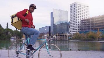 Portrait of a delivery man sitting on a bicycle and texting on the smartphone. City Background. video
