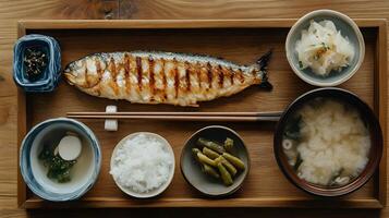 A quiet morning scene with a simple Japanese breakfast of grilled fish, miso soup, rice, and pickles, arranged neatly on a wooden tray with chopsticks photo