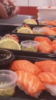 Master sushi chef carefully puts soy into small boxes alongside fresh nigiri. Each nigiri is delicately arranged, with soy placed precisely, enhancing the visual appeal and taste of the nigiri. video