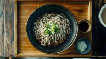 A bowl of chilled zaru soba noodles served on a bamboo tray with a small dish of dipping sauce, garnished with finely chopped green onions and grated daikon photo