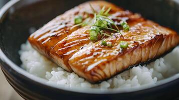 A close-up of a beautifully grilled slice of unagi glazed in sweet soy sauce, placed elegantly over a bed of white rice in a traditional ceramic bowl photo