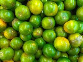 Pile of Glossy Green Oranges with Natural Yellow Hints photo