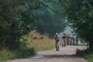 Elite military unit parading and securing the forest, utilizing drones for terrain scanning and reconnaissance, showcasing their advanced skills and specialized training in high risk operations photo