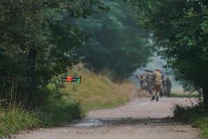 Elite military unit parading and securing the forest, utilizing drones for terrain scanning and reconnaissance, showcasing their advanced skills and specialized training in high risk operations photo