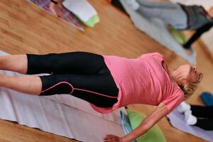 Senior Woman Practicing Back Stretches in a Sunlit Space for Optimal Health and Well Being photo