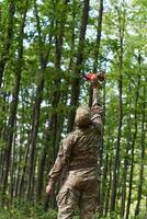 Elite military unit, equipped with state-of-the-art technology including a drone, strategically navigates and surveys dangerous wooded terrain, showcasing their precision, cooperation, and specialized photo