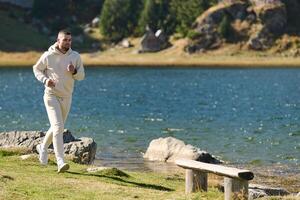 Athletic man maintains his healthy lifestyle by running through the scenic mountain and lakeside environment, showcasing a commitment to fitness and well-being photo