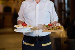 A courteous waiter provides impeccable service to an elderly family and their friends, creating a convivial atmosphere as they gather for a shared lunch, indulging in the diverse and delectable photo