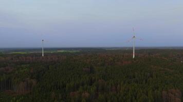 Aerial view of wind farm turbines set up in countryside with forest. Producing power using energy of nature. Incorporating technology into environment of nature. Cloudy sky. Electricity production. video
