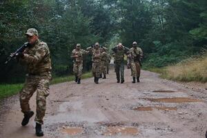 A group of elite soldiers leads captives through a military camp, showcasing a tense atmosphere of detention and security operations photo