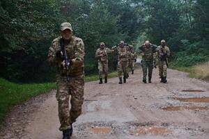 A group of elite soldiers leads captives through a military camp, showcasing a tense atmosphere of detention and security operations photo