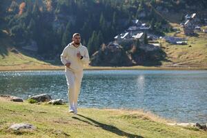 Athletic man maintains his healthy lifestyle by running through the scenic mountain and lakeside environment, showcasing a commitment to fitness and well-being photo