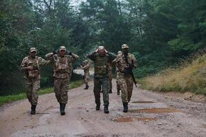 A group of elite soldiers leads captives through a military camp, showcasing a tense atmosphere of detention and security operations photo