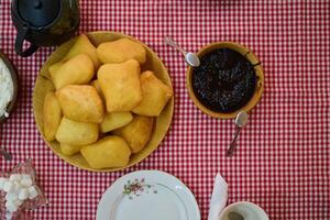 An enticing top down view captures a delightful breakfast tableau, featuring freshly baked bread, delectable jam, and a comforting cup of tea a simple yet satisfying morning feast. photo