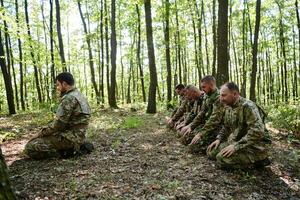 A dedicated group of soldiers engages in Islamic prayer amidst the challenging and perilous conditions of a military operation in dense forested areas photo