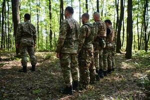 A dedicated group of soldiers engages in Islamic prayer amidst the challenging and perilous conditions of a military operation in dense forested areas photo