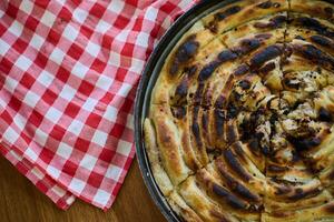 Exquisitely prepared, this traditional Bosnian dish showcases a mouthwatering pie under its lid, perfectly baked and ready to delight guests, embodying the rich culinary heritage and inviting flavors photo