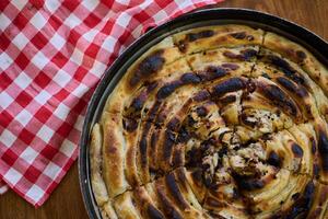Exquisitely prepared, this traditional Bosnian dish showcases a mouthwatering pie under its lid, perfectly baked and ready to delight guests, embodying the rich culinary heritage and inviting flavors photo