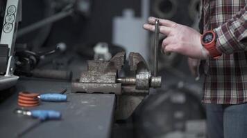 A male mechanic uses a metal vise to repair a scooter in the maintenance store. A repairman using a vises to clamp a part from a pushbike in the workshop. Bicycle and scooter repair service. video