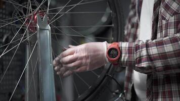 Bicycle repair in workshop. Man bike mechanic fixes wheel, tension spokes with special tool on stand for adjusting wheels. Handyman fixes wheel spokes by working in cycle service station. video