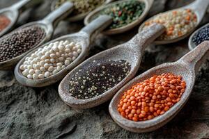 CloseUp of Various Colorful Legumes in Rustic Clay Spoons on Stone Surface photo