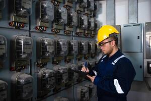 Electrical maintenance engineer is checking Electricity meter, main distribution board and write down value of electricity on a clipboard photo