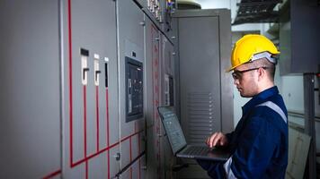 Electrical engineer check the operation of the main electrical control panels system on laptop photo