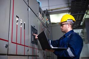 Electrical engineer check the operation of the main electrical control panels system on laptop photo
