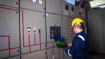 Electrical maintenance engineer is checking .Electricity meter, main distribution board and write down value of electricity on a laptop photo