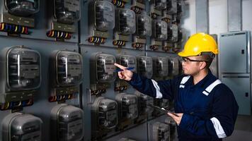 Electrical maintenance engineer is checking Electricity meter, main distribution board and write down value of electricity on a clipboard photo