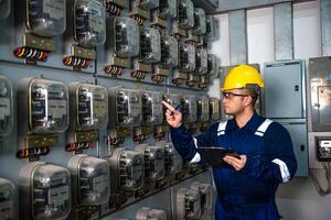 Electrical maintenance engineer is checking .Electricity meter, main distribution board and write down value of electricity on a clipboard photo